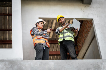 Asian people, two man, holding blueprints Structural engineers examine structural plans for office buildings and housing developments on-site, discussing work at construction site.