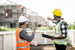 © R Photography - Asian people, two man, holding blueprints Structural engineers examine structural plans for office buildings and housing developments on-site, discussing work at construction site.