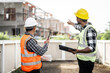 © Ratirath - Asian people, two man, holding blueprints Structural engineers examine structural plans for office buildings and housing developments on-site, discussing work at construction site.