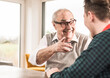 © Westend61 - Happy senior man gesturing and talking to grandson at home