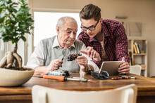 Young man helping grandfather in repairing miniature train at home