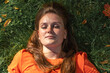 © Westend61 - Smiling redhead woman with sunlight over face relaxing on grass
