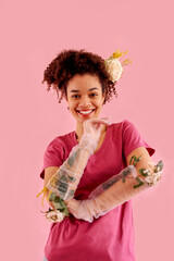 Wall Mural - Happy young smiling female african ethnicity in pink clothes, transparent gloves and flowers