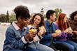 © PintoArt - multicultural friends on university break eating a sandwich while laughing