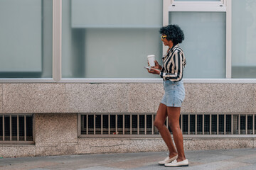 Wall Mural - woman walking with mobile phone and cup