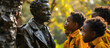 Black schoolchildren admire a statue of an African American man,