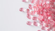 Close up of a pile of pink pills, vitamins on a white background.	
