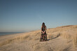 © Milou Dirks - woman in long dress standing alone in the dunes near the beach