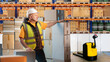 Customs warehouse employee. Man stands inside vault. Loader in warehouse with boxes and racks. Customs warehouse for checking goods. Man warehouseman looks away. Storage worker in yellow vest