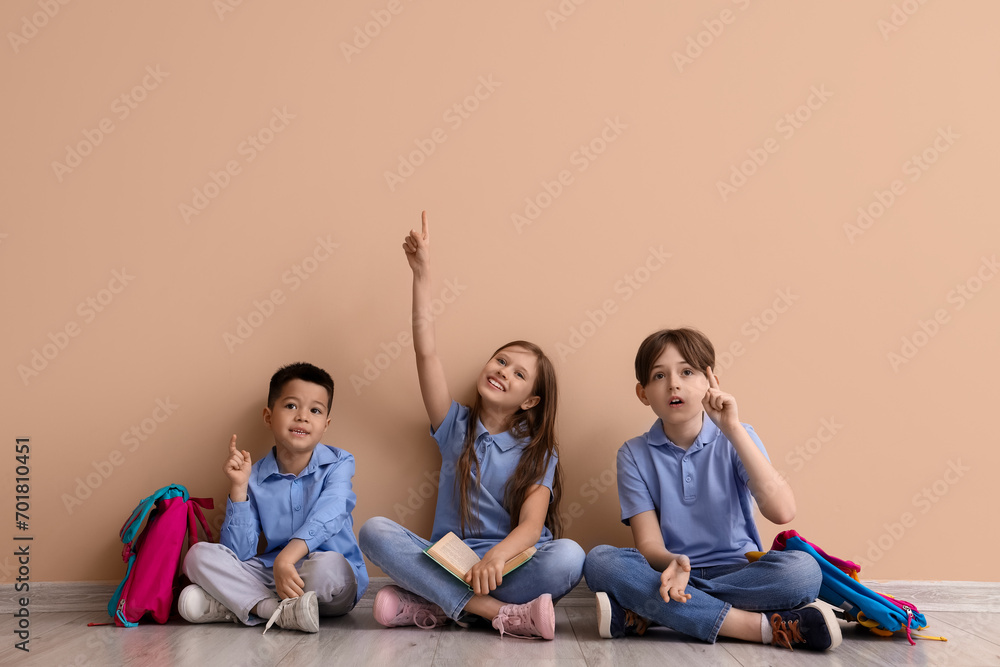 Little pupils pointing at something near beige wall