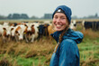 Portrait of a happy, young farm woman in front of a cow herd