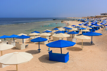 Wall Mural - Sun loungers with umbrellas on the beach in Marsa Alam at sunrise, Egypt