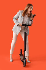 Poster - Portrait of panicked businesswoman with kick scooter talking by phone on orange background