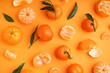 Tasty tangerines with leaves on orange background