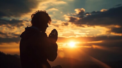 Silhouette of a praying man against the background of sunrise