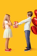 Sticker - Little boy greeting girl with gift on yellow background. Valentine's Day celebration