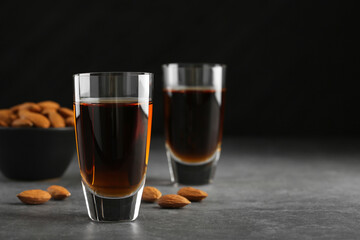 Canvas Print - Glasses with tasty amaretto liqueur and almonds on gray table, closeup. Space for text