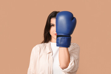 Wall Mural - Young woman in boxing gloves on beige background. Feminism concept