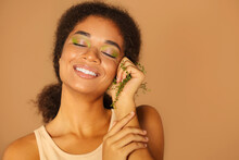 Young Happy African American Woman With Closed Eyes Holding Twig With Leaves In Her Fist And Smiling