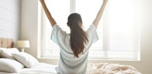 A Graceful Asian Woman Waking Up in a Simple White Room, Embracing the Morning Air with a Stretch. Generative AI