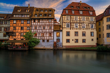 Wall Mural - Ornate traditional half timbered houses with blooming flowers along the canals in the Petite France district of Strasbourg, Alsace, France at sunset