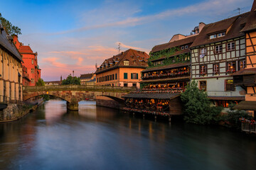 Poster - Ornate traditional half timbered houses with blooming flowers along the canals in the Petite France district of Strasbourg, Alsace, France at sunset