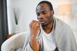 © Serhii - ill african american man in warm scarf with nose spray