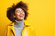 Happy afro girl standing against yellow background with copy space