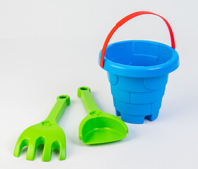Children's toy bucket with shovels for playing in the sand on a white background.