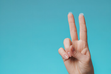 close-up round acne patch on finger on blue background. acne patches for treatment of pimple and ros