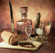 Antique-style still life with alcohol, vodka, canned fish, bread and cucumber.