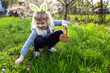 Little girl gathering colorful egg in park. Easter hunt concept