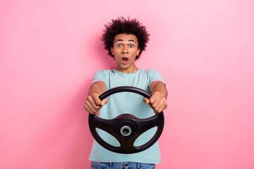 Wall Mural - Photo portrait of attractive young man steering wheel terrified reaction dressed stylish blue clothes isolated on pink color background