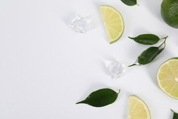 Canvas Print - Flat lay composition with fresh limes, leaves and ice cubes on white background. Space for text