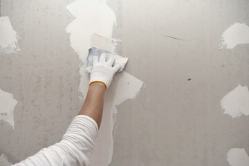 plasterwork and wall painting preparation. close up hand of craftsman applying filling drywall patch