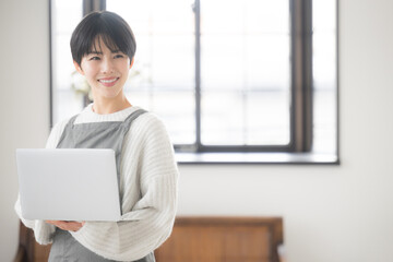 Wall Mural - A woman who uses a computer in her room to think about sales, etc., like a sales clerk in a store or in the hospitality industry.