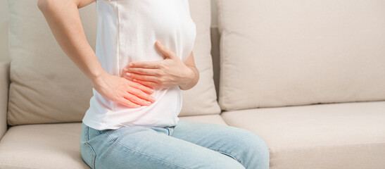 Woman having abdomen pain on the sofa at home. Liver cancer and Tumor, kidney cancer, Jaundice, Viral Hepatitis, Cirrhosis, Failure, Enlarged, Hepatic Encephalopathy, Stomach and health concept