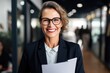 A smiling mature businesswoman with glasses from the HR department holds a resume at a job interview