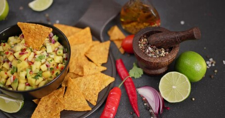 Canvas Print - Freshly made Mango salsa in black ceramic bowl and tortilla chips on dark background