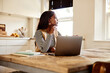 © Flamingo Images - Businesswoman using a laptop in her kitchen