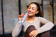 © Flamingo Images - Laughing woman drinking water in a gym