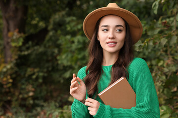 Sticker - Beautiful young woman in stylish warm sweater with book outdoors, space for text