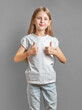 Happy child, little girl showing thumbs up gesture in a white T-shirt