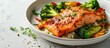 close up of broiled salmon chunks with steamed broccoli florets in white bowl on white wood table landscape view. with copy space image. Place for adding text or design