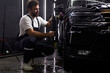 © Roman - Side view on caucasian man auto mechanic worker polishing car at automobile repair and renew service station shop by power buffer machine. Copy Space
