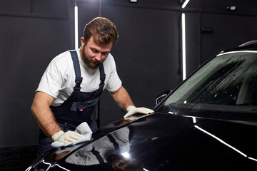 Canvas Print - Worker in uniform saw scratch on paint surface of car, polishing and repairing damage using rag in renew service station shop. repair man at work place