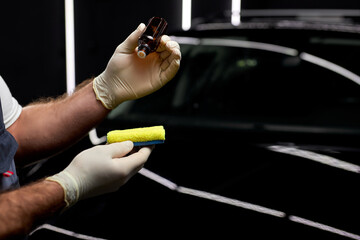 Poster - close-up hands applying oil from small jar to rag to clean the surface of auto, in repair and renew service station shop