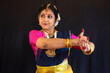 Beautiful Indian classical dancer in traditional costume performing dance on black background in close up view