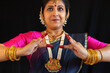 Beautiful Indian female classical dancer performing Bharatanatyam postures on black background