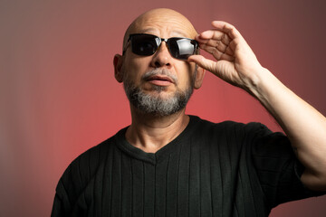 Wall Mural - White, bald man, wearing sunglasses, confident and serious looking towards the camera.